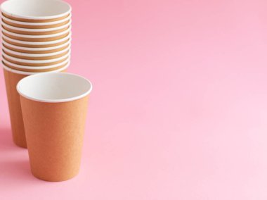 Pembe arka planda tek kullanımlık kağıt bardak. Ekoloji, plastik çevre kirliliği, atık geri dönüşümü kavramı. kopyalama alanı.