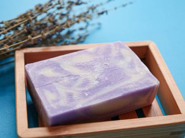 Mavi arka planda lavanta çiçeği ve sabun kompozisyonu. Doğal el yapımı ürün kavramı, yakın plan.