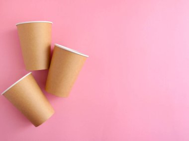 Pembe arka planda tek kullanımlık kağıt bardak. Ekoloji, plastik çevre kirliliği, atık geri dönüşümü kavramı. Düz alan, kopyala.