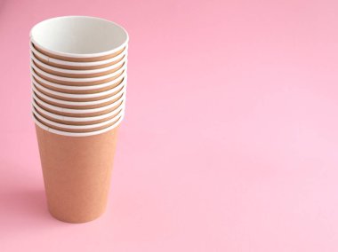 Pembe arka planda tek kullanımlık kağıt bardak. Ekoloji, plastik çevre kirliliği, atık geri dönüşümü kavramı. kopyalama alanı.