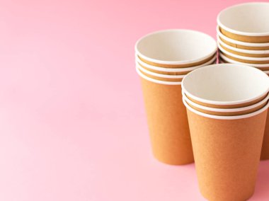 Pembe arka planda tek kullanımlık kağıt bardak. Ekoloji, plastik çevre kirliliği, atık geri dönüşümü kavramı. kopyalama alanı.