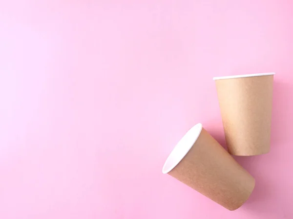 Pembe arka planda tek kullanımlık kağıt bardak. Ekoloji, plastik çevre kirliliği, atık geri dönüşümü kavramı. Düz alan, kopyala.