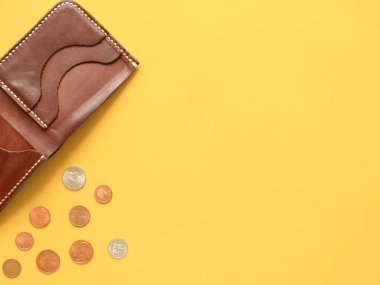 Kahverengi cüzdan, dağınık dolar ve sarı arka planda avro paraları. Son para, yoksulluk, işsizlik, iş kaybı, tasarruf kavramı. Düz konum, telif alanı.