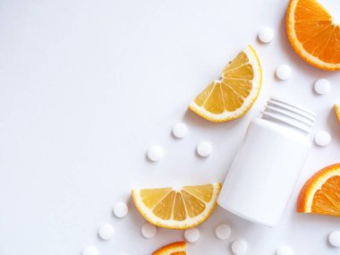 Beyaz arka planda limon portakallı vitamin hapları ve şişe. Telif alanı, düz yatak, yakın çekim. Bağışıklık sistemini, ilacı ve tabletleri güçlendirme kavramı