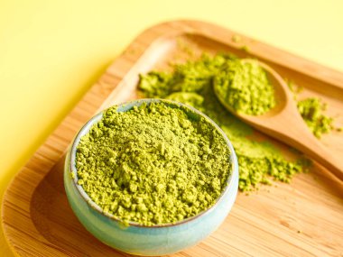 Sarı arka planda ahşap salver üzerine kaşık ile kibrit çayı. Sağlıklı içecekler, detoks, yakın çekim..