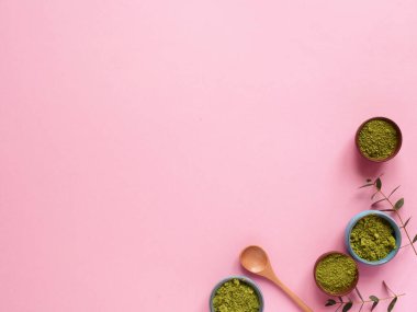 Küçük kavanozda kibrit çayı, tahta kaşık ve pembe arka planda okaliptüs yaprağı. Sağlıklı içecek, detoks, telif alanı, düz alan, üst görünüm kavramı.