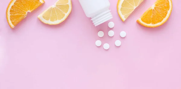 Pembe arka planda limonlu ve turunculu şişeden alınmış vitamin hapları. Kopyalama alanı, düz döşeme, pankart. Bağışıklık sistemini, ilacı ve tabletleri güçlendirme kavramı