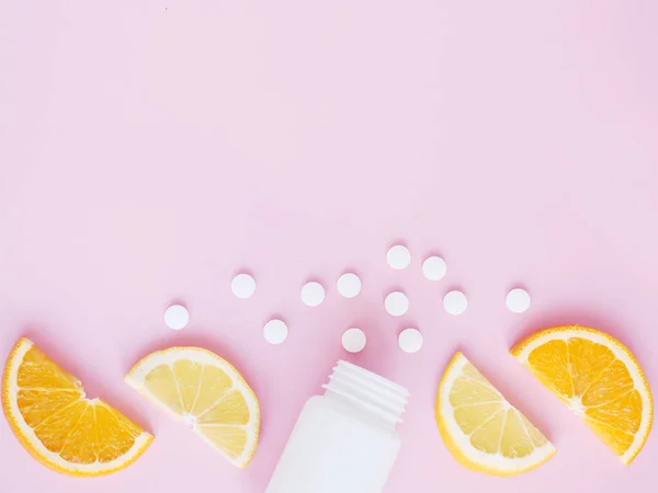 Pembe arka planda limonlu ve turunculu şişeden alınmış vitamin hapları. Telif uzayı, düz yatış. Bağışıklık sistemini, ilacı ve tabletleri güçlendirme kavramı