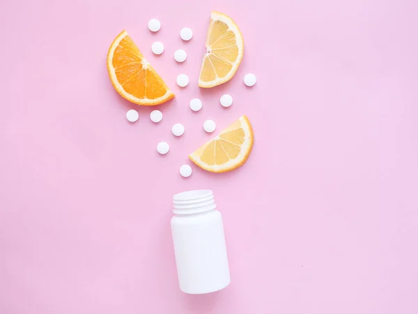 Pembe arka planda limonlu ve turunculu şişeden alınmış vitamin hapları. Kopyalama alanı, dizayn için alan, düz alan. Bağışıklık sistemini, ilacı ve tabletleri güçlendirme kavramı