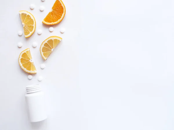 Beyaz arka planda limon portakallı vitamin hapları ve şişe. Telif uzayı, düz yatış. Bağışıklık sistemini, ilacı ve tabletleri güçlendirme kavramı