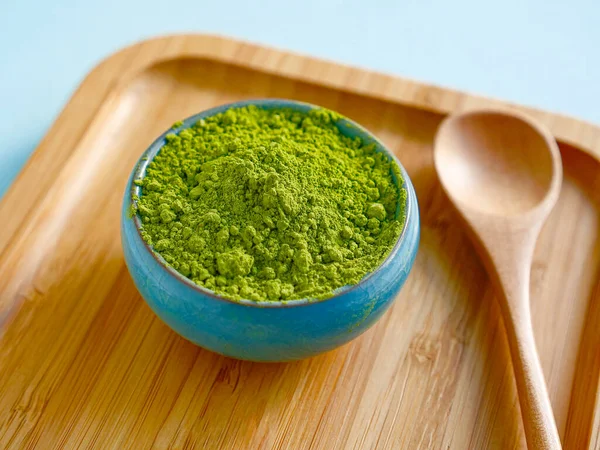 Mavi arka planda ahşap salver üzerine kaşık ile kibrit çayı. Sağlıklı içecekler, detoks, yakın çekim..