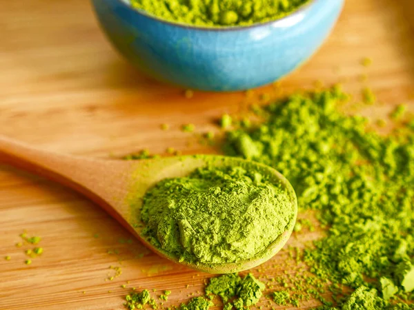 Ahşap arka planda kaşıkla kibrit çayı. Sağlıklı içecekler, detoks, yakın çekim.