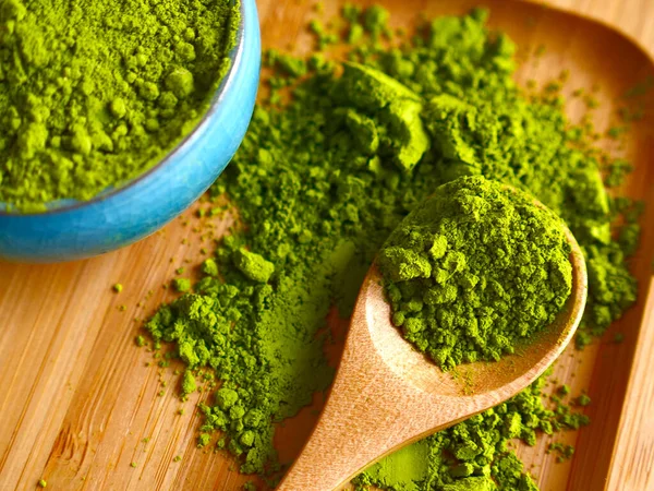 Ahşap arka planda kaşıkla kibrit çayı. Sağlıklı içecekler, detoks, yakın çekim.