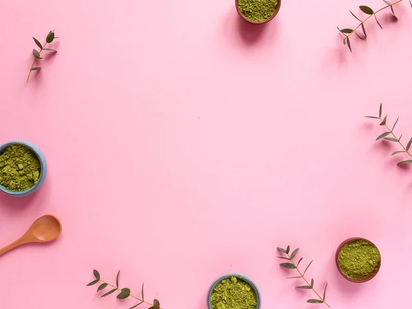 Küçük kavanozda kibrit çayı, tahta kaşık ve pembe arka planda okaliptüs yaprağı. Sağlıklı içecek, kopyalama alanı, düz alan, üst görünüm, çerçeve