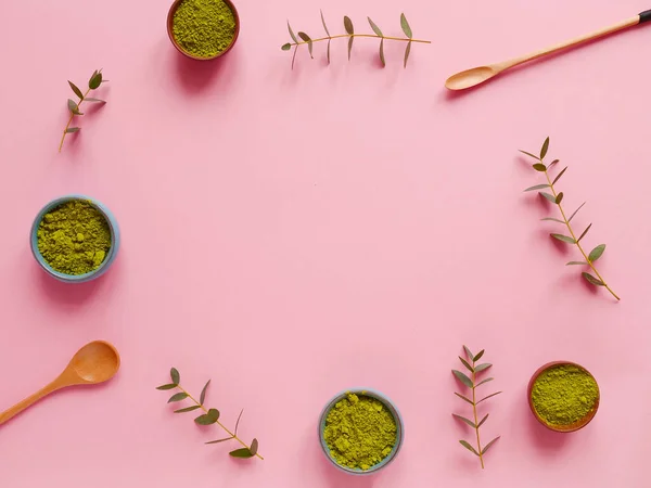 Küçük kavanozda kibrit çayı, tahta kaşık ve pembe arka planda okaliptüs yaprağı. Sağlıklı içecek, kopyalama alanı, düz alan, üst görünüm, çerçeve