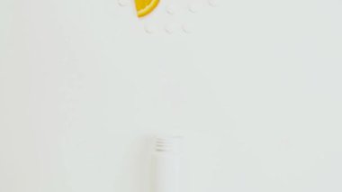 Dağılmış vitamin hapları ve limon portakalı beyaz arka planda şişede hareket ediyor. Hareket animasyonunu durdur. Bağışıklık sistemini, ilacı ve tabletleri güçlendirme kavramı