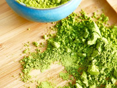 Ahşap arka planda mavi kavanozlu dağınık kibrit çay dokusu. Sağlıklı içecekler, detoks, yakın çekim.