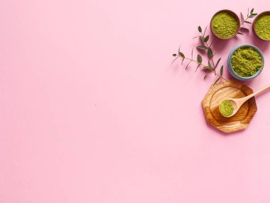 Küçük kavanozda kibrit çayı, tahta kaşık ve pembe arka planda okaliptüs yaprağı. Sağlıklı içecek, kopyalama alanı, düz alan, üst görünüm kavramı.