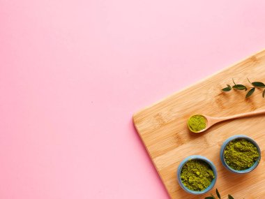 Ahşap kesme tahtasında kibrit çayı, pembe arka planda kaşık ve yaprak. Sağlıklı içecek, detoks, telif alanı, düz yatak
