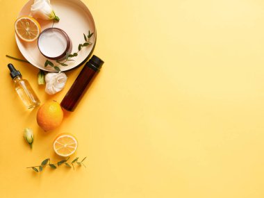 Krem, losyon, yağ, çiçek, turunçgil ve sarı arka planda okaliptüs içeren yassı beste. Güzelliği kavramsal olarak doğal vitamin kozmetik ürünü, cilt bakımı, telif alanı, üst görünüm