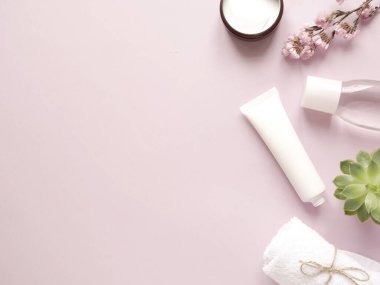 bakım ürünleri losyonu, krem, bitki, havlu. Pembe arka planda banyo aksesuarları, üst manzara, telif alanı. Ev konseptinde vücut bakımı güzellik tedavileri, organik ürünler, sabah rutini.