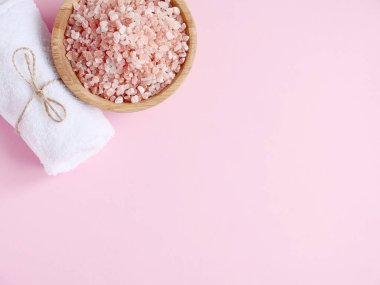 Spa yassı kompozisyonu. Deniz tuzu, pembe arka planda banyo havlusu. Kopyalama alanı, üst görünüm. Evde bakım konsepti, rahatlama ve dinlenme, banyo prosedürü.