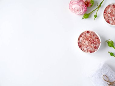 Spa yassı kompozisyonu. Kavanozda deniz tuzu, havlu, beyaz arka planda çiçek. Üst Manzara. Günlük bakım konsepti, rahatlama ve dinlenme, banyo prosedürü.