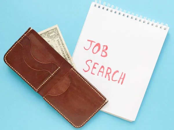 notebook with job search phrase, brown wallet, one dollar on blue background. looking for a work, last money, poverty, unemployment, job loss concept. Flat lay.