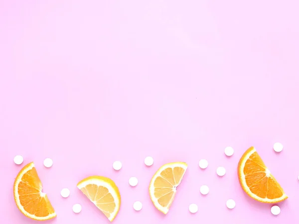 Pembe arka planda limonlu ve turuncu vitamin hapları. Telif uzayı, düz yatış. Bağışıklık sistemini, ilacı ve tabletleri güçlendirme kavramı