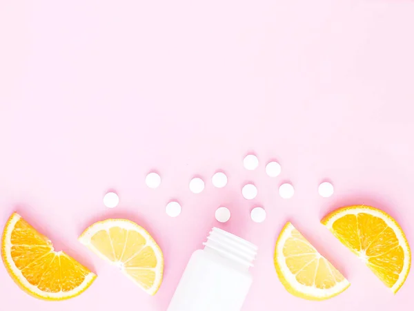 Pembe arka planda limonlu ve turunculu şişeden alınmış vitamin hapları. Telif uzayı, düz yatış. Bağışıklık sistemini, ilacı ve tabletleri güçlendirme kavramı