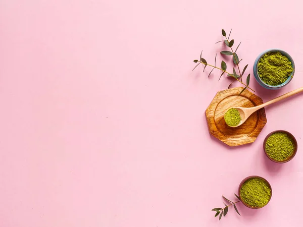 Küçük kavanozda kibrit çayı, tahta kaşık ve pembe arka planda okaliptüs yaprağı. Sağlıklı içeceği, boşluğu, düzlüğü, üst görünümü kavramsallaştır.