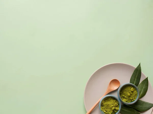 Gri tabakta kibrit çayı, büyük arka planda kaşık ve yaprak. Sağlıklı içecek, kopyalama alanı, düz alan, üst görünüm kavramı.