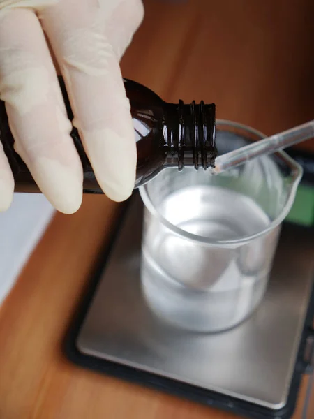 Masanın üzerinde cam şişe olan eller. Evde doğal kozmetik ürünleri yaratmak kavramı