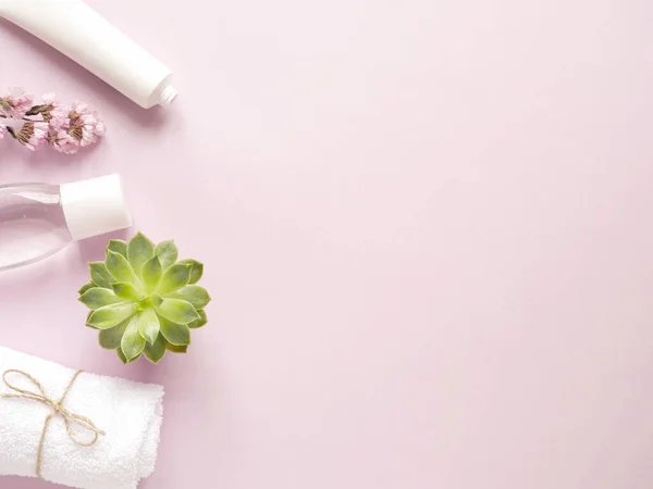 bakım ürünleri losyonu, krem, bitki, havlu. Pembe arka planda banyo aksesuarları, üst manzara, telif alanı. Ev konseptinde vücut bakımı güzellik tedavileri, organik ürünler, sabah rutini.