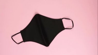 Siyah yüz koruyucu yeniden kullanılabilir maske ve çiçek pembe arka planda yüz oluşturur. Güzellik endüstrisinde konsept koruma ve sağlık. Hareketi durdur.