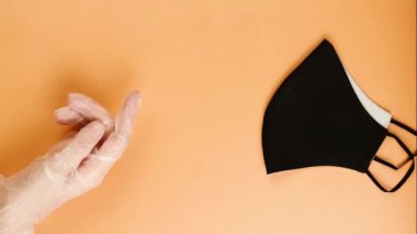 Siyah yüz koruyucu, turuncu arka planı olan yeniden kullanılabilir maske. Konsept koruma ve sağlık.