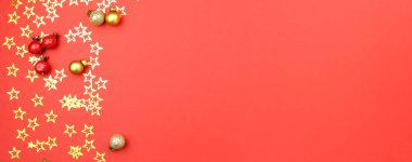 Kırmızı arka planda altın konfeti yıldızları, balolar ve böğürtlenlerle Noel süslemesi. Tatil atmosferi, yeni yıl kutlamaları, tebrik kartları. Düz çizgi, üst görünüm, çerçeve, telif alanı, pankart.