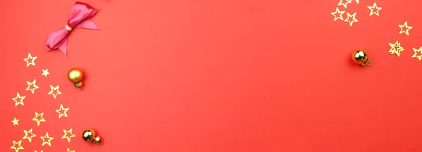 Kırmızı arka planda altın konfetili Noel süslemeleri, toplar. Tatil atmosferi, yeni yıl kutlamaları, tebrik kartları. Düz çizgi, üst görünüm, telif alanı, pankart.
