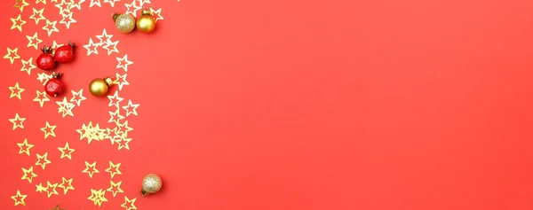 Kırmızı arka planda altın konfeti yıldızları, balolar ve böğürtlenlerle Noel süslemesi. Tatil atmosferi, yeni yıl kutlamaları, tebrik kartları. Düz çizgi, üst görünüm, çerçeve, telif alanı, pankart.