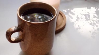 Sıcak çay fincanı, gölgelerin hareketi, beyaz arka planda yanan mum. Ev atmosferi, aromaterapi, doğal yağ yakıcı, sağlık terapisi, dinlenme zamanı, kendin için.
