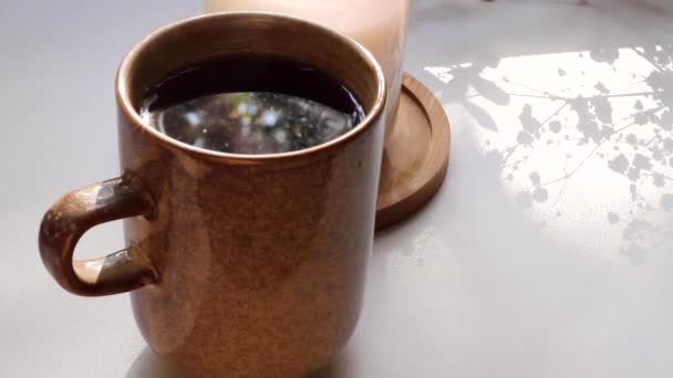 Gemütliche Teetasse Mit Bewegung Der Schatten Brennende Kerze Auf Weißem — Stockvideo