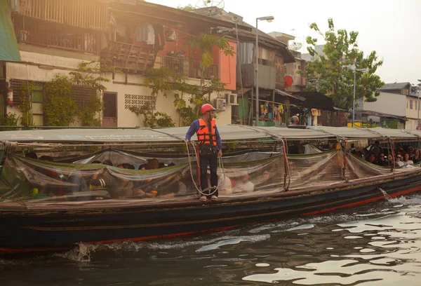 BANGKOK, THAILAND - 11 Ocak 2019. Nehirde bir tekne ve kıç tarafında bilet kontrolörü. Bangkok, Tayland 'da toplu taşıma