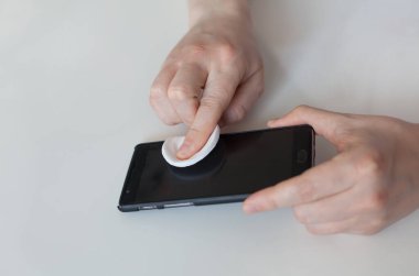 Telefonunu pamukla silen bir adam. Covid 19 koronavirüs karantinası sırasında dezenfeksiyon