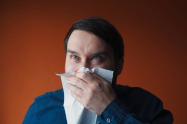 Kafkasyalı bir adam yüzünde komik bir ifadeyle mendile burnunu sümkürdü.