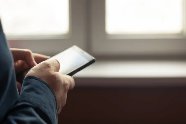 Hombre Sosteniendo Teléfono Celular Sus Manos Cerca Una Ventana Primer — Foto de Stock