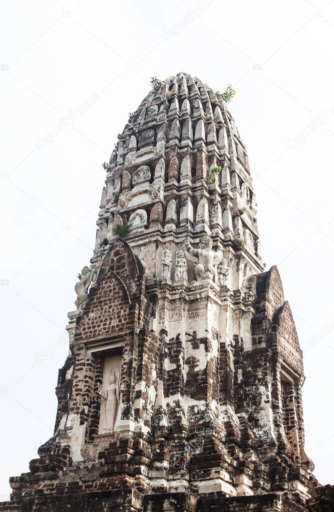 Old asian buddhist pagoda in Thailand. Upper part with plants and stone carving on it