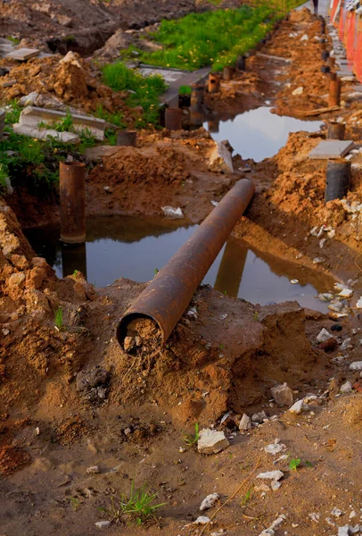 Rusty iron tube laying in mud. Construction works. Vertical shot