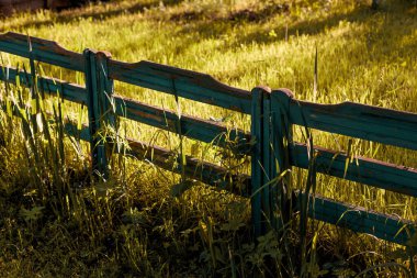 Altın saatinde, kontrastlı ışıkla süslü eski püskü ahşap çitler.