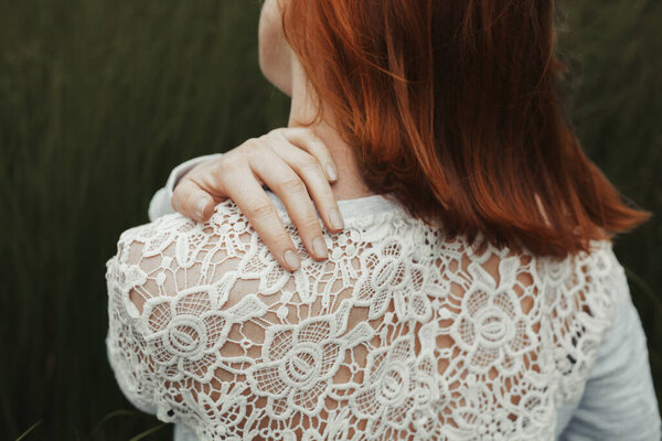 Ginger girl touching her shoulder closeup. Shot from back