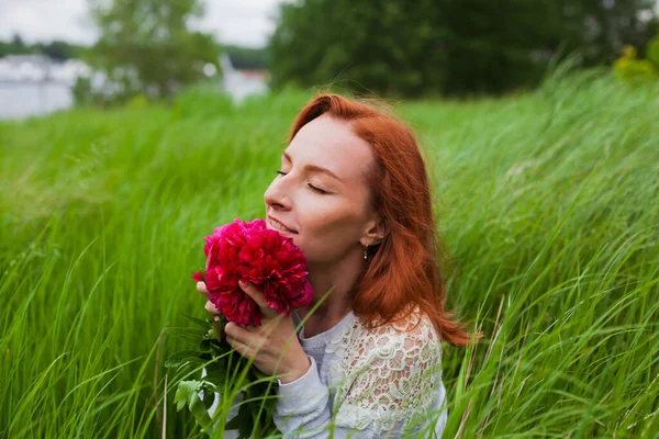 Uśmiechnięta Ruda Dziewczyna Piwoniami Zielonej Trawie Ujęcie Profilowe — Zdjęcie stockowe